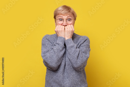 Scared worried mature caucasian woman, biting nails.
