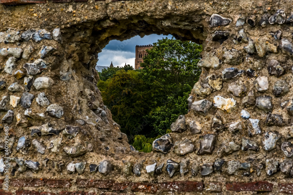 A glimpse of the Cathedral through a hole in the ancient Roman Wall in  Verulamium Park, St Albans, UK in the summertime