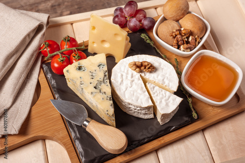 wooden tray for breakfast with brie cheese, honey, walnuts, tomato. cheese dessert on the wooden tray. side view