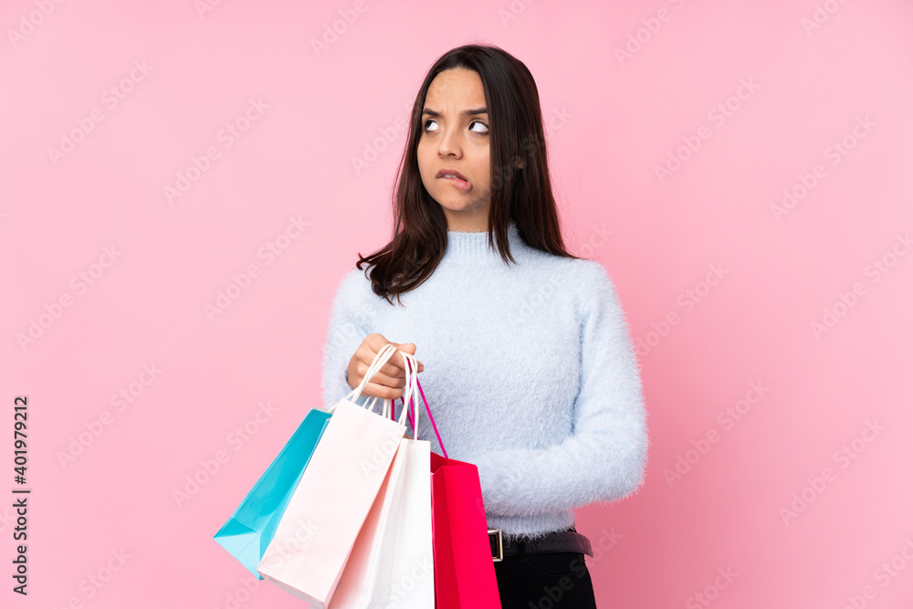 Young woman with shopping bag over isolated pink background with confuse face expression