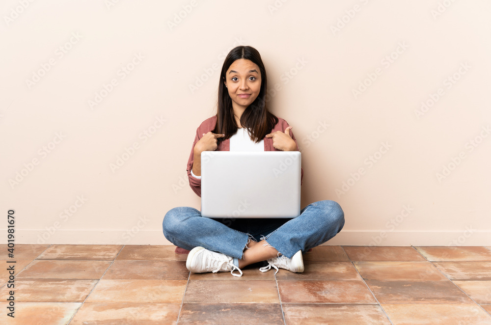 Young mixed race woman with a laptop sitting on the floor with surprise facial expression Young mixed race woman with a laptop sitting on the floor with surprise facial expression
