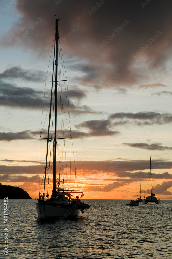 Anchoring ships in tropical bay at sunset. Small yachts and catamarans on sea water during dusk. Santa Lucia. Caribbean lifestyle themes