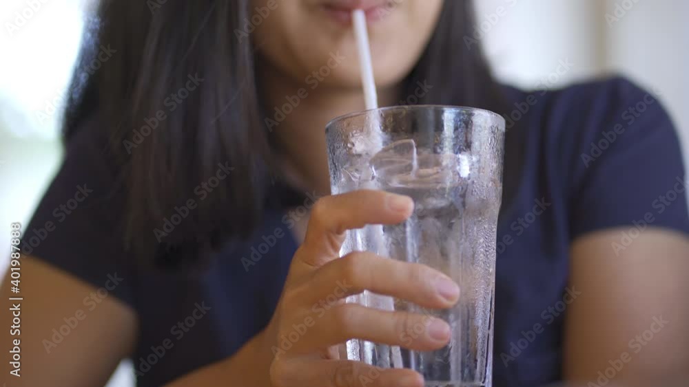 4K clear glass with ice and water inside, the background was a woman holding a glass and sucking water 4K clear glass with ice and water inside, the background was a woman holding a glass and sucking water
