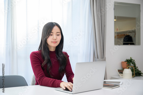 リビングでパソコン作業をする若い日本人女性