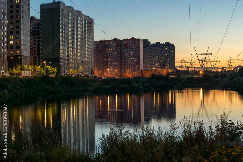 multi-storey residential area on the river Bank in the light of the setting sun in the evening and reflections in the water