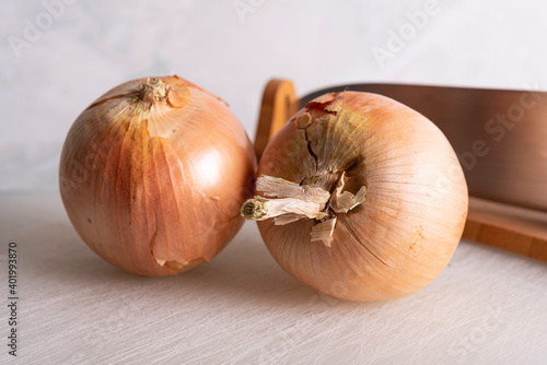 Onions being Sliced on White Cutting Board With Chef's Knif and Wood Stand