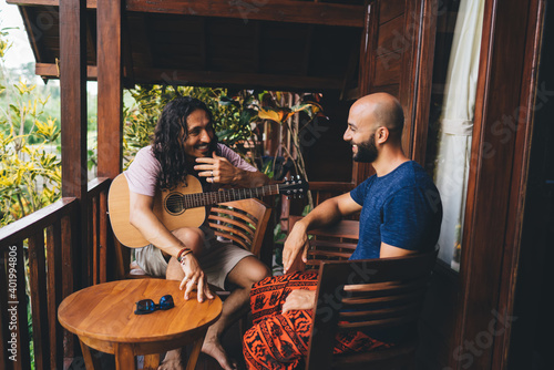 Cheerful multiracial bearded male friends with guitar
