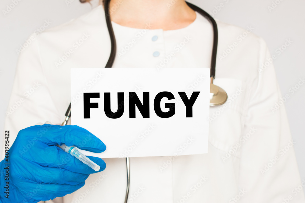 The doctor's blue - gloved hands show the word FUNGY - . a gloved hand on a white background. Medical concept. the medicine The doctor's blue - gloved hands show the word FUNGY - . a gloved hand on a white background. Medical concept. the medicine