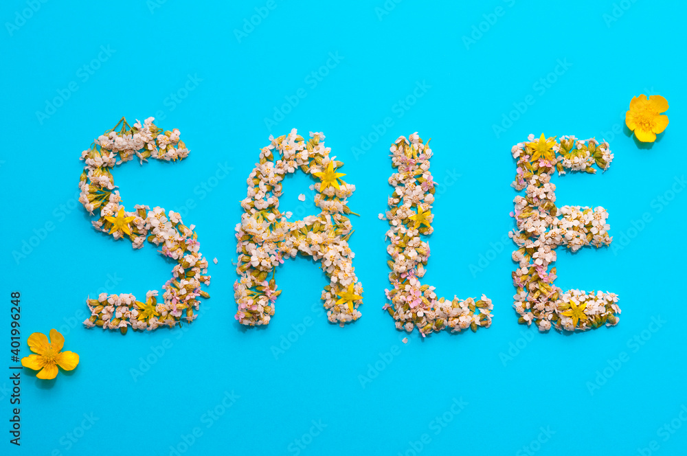 Word sale made of small flowers top view on a blue paper background