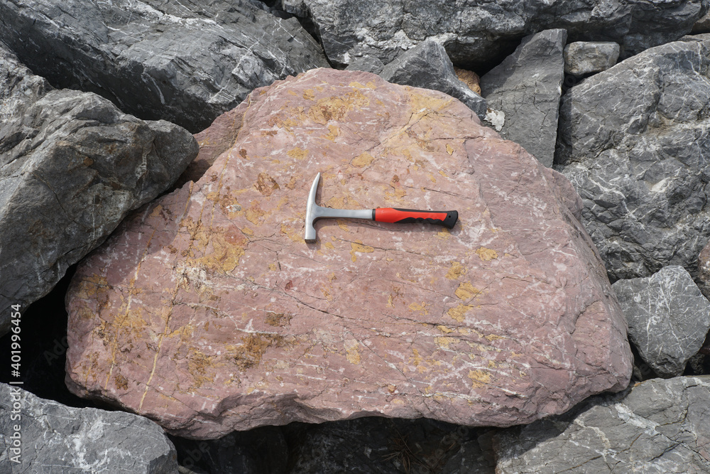 Geological Hammer on raw red limestone in the natural background