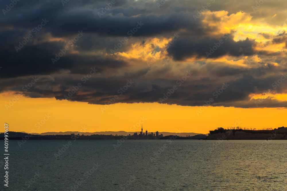 The distant skyline of Auckland, New Zealand, at sunset, from far out on Waitemata Harbour
