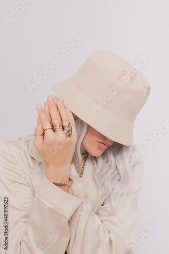 Urban street style Blonde. Details of everyday look. Casual beige outfit and accessories. Bucket hat, chain and rings. Trendy Minimalist fashion