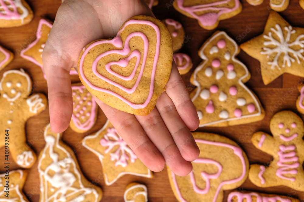 Cookies for Valentines Day in woman hands in the background of gingerbread. 