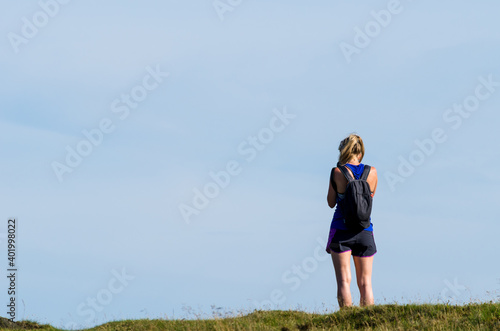 Active woman with a backpack hiking outdoors against the sky