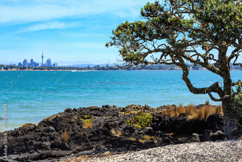 The distant skyline of Auckland, New Zealand, seen from the shore of Rangitoto Island The distant skyline of Auckland, New Zealand, seen from the shore of Rangitoto Island