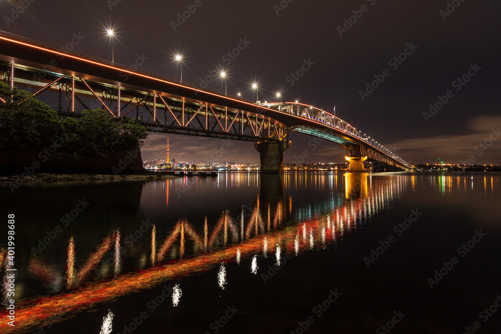 The Auckland Harbour Bridge, Auckland, New Zealand, at night, reflected in the waters of Waitemata Harbour