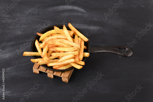 Fried fries in a frying pan on a wooden pallet trivet.