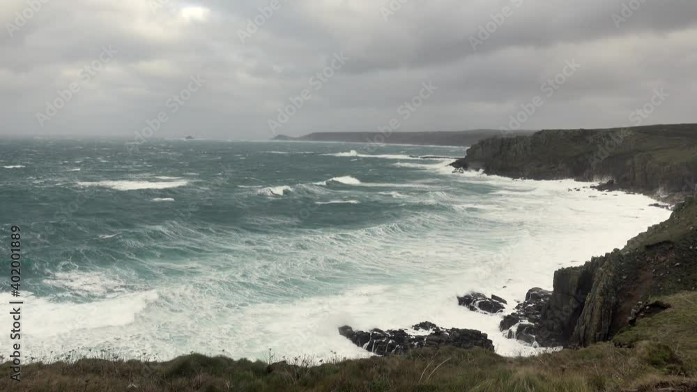Stormy rough seas and breaking Atlantic ocean waves over rocks at Lands End Cornwall, UK after Storm Bella gale force winds surge through the coastline. Stormy rough seas and breaking Atlantic ocean waves over rocks at Lands End Cornwall, UK after Storm Bella gale force winds surge through the coastline.