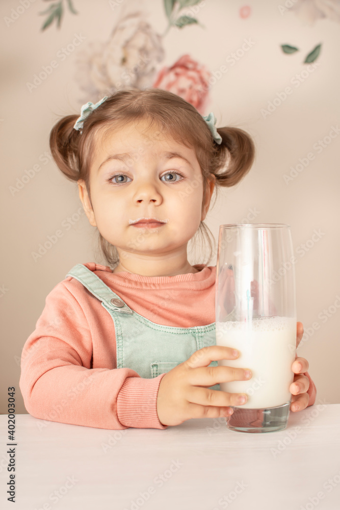 Portrait of adorable cute baby girl drinking milk. Beautiful child drink kefir. Close up of funny toddler enjoying healthy fresh organic milk. Portrait of adorable cute baby girl drinking milk. Beautiful child drink kefir. Close up of funny toddler enjoying healthy fresh organic milk.