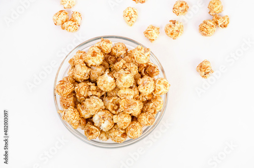 Caramel popcorn in a glass bowl on a white background