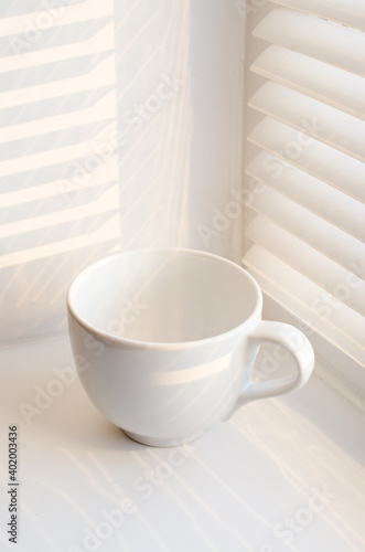 White mug on a white background with blinds and beautiful light