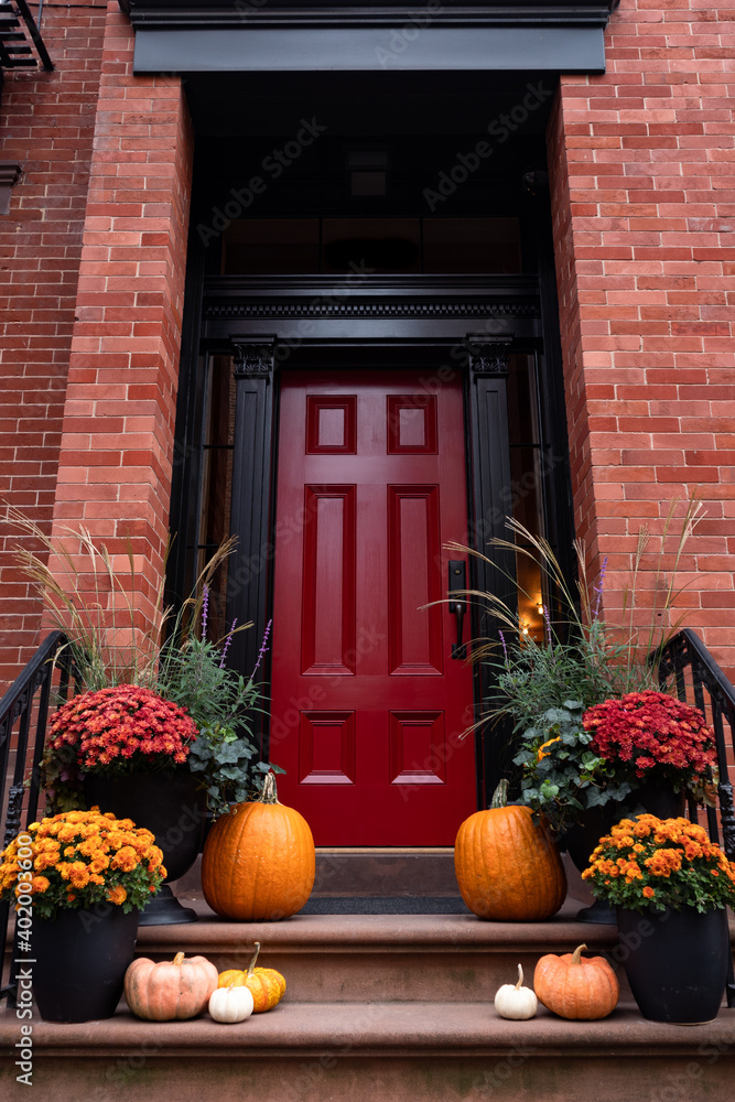Colorful Pumpkins and Flowers on the Stairs of an Old Brownstone Home with a Red Door in New York City during Autumn