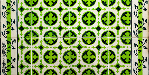 Portuguese traditional tiles Azulejos with green floral and geometrical pattern on a white background.