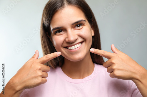 Young woman with healthy teeth on light background. Cosmetic dentistry