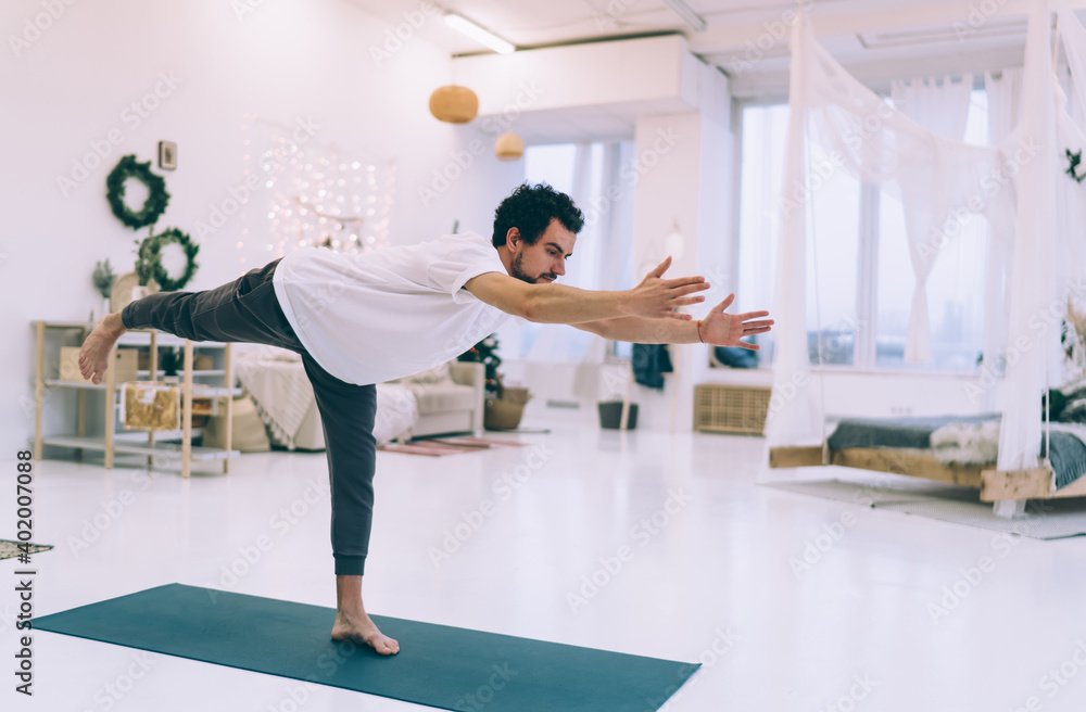 Man doing balancing stick pose on sport mat Man doing balancing stick pose on sport mat