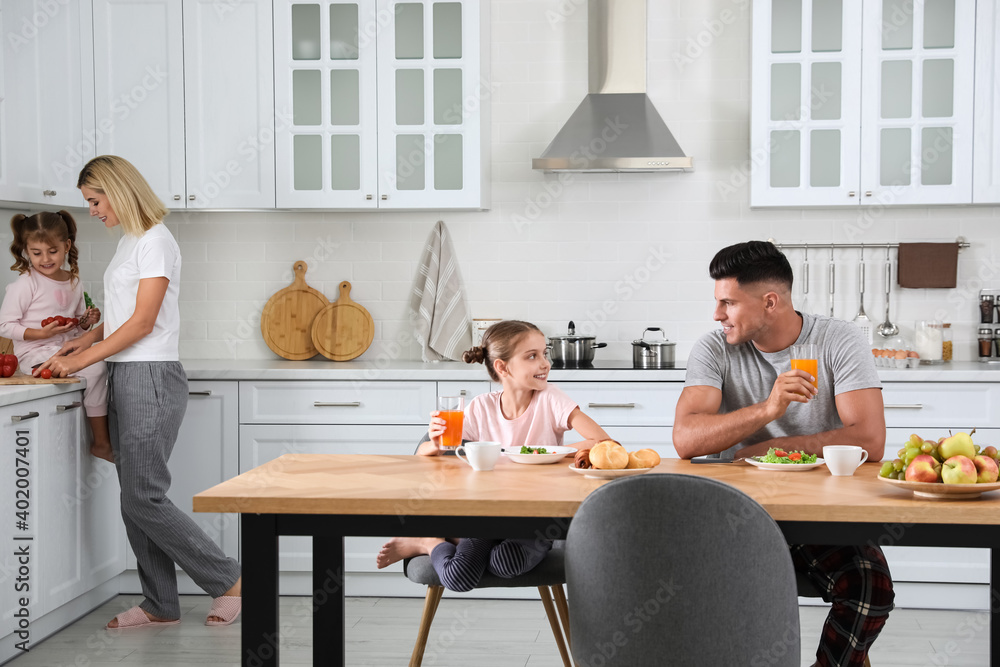 Happy family having breakfast together at table in modern kitchen Happy family having breakfast together at table in modern kitchen