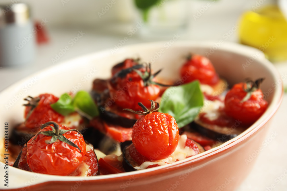 Baked eggplant with tomatoes, cheese and basil in dishware on table, closeup Baked eggplant with tomatoes, cheese and basil in dishware on table, closeup
