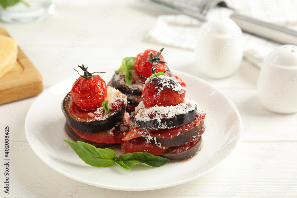 Baked eggplant with tomatoes, cheese and basil served on white wooden table, closeup