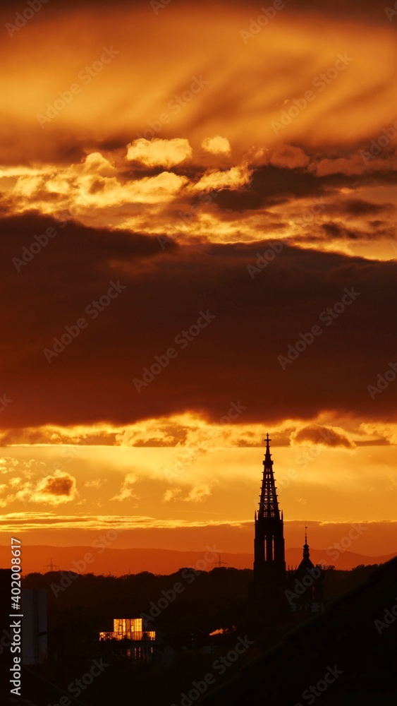 Kirchturm im Sonnenuntergang mit Wolkenspiel in Abenddämmerung