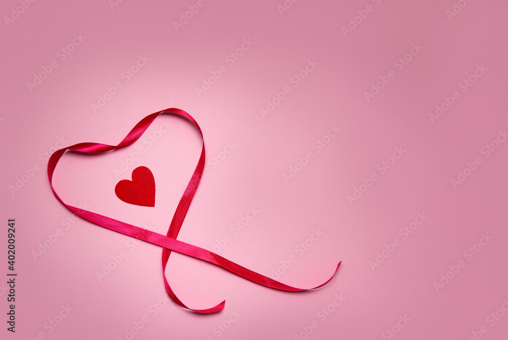 heart made of red ribbon on a pink background. Valentine's Day