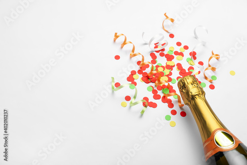 Composition with confetti and bottle of champagne on white background. Space for text