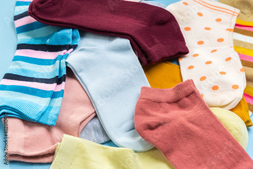 Many multicolored new socks stacked against a blue background. top view.