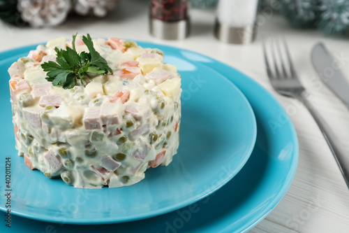 Traditional russian salad Olivier served on white wooden table, closeup