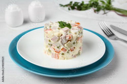 Traditional russian salad Olivier served on white wooden table
