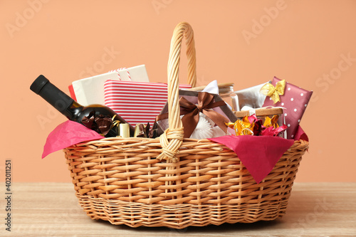 Wicker gift basket with bottle of wine on wooden table