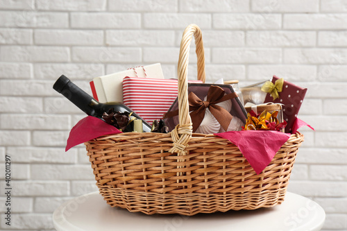 Cuadro en lienzo Wicker gift basket with bottle of wine on table near white brick wall