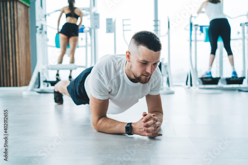 Strong sporty man doing plank on floor in gym