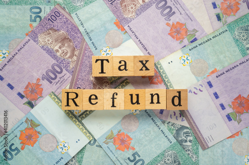 Text TAX REFUND on wooden cubes with a bundle of the banknote. Flat lay view concept.