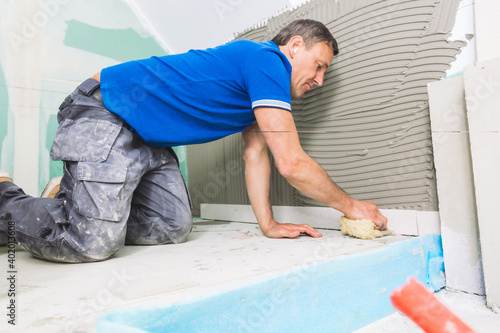 man installing large format tiles on wall. home renovation concept