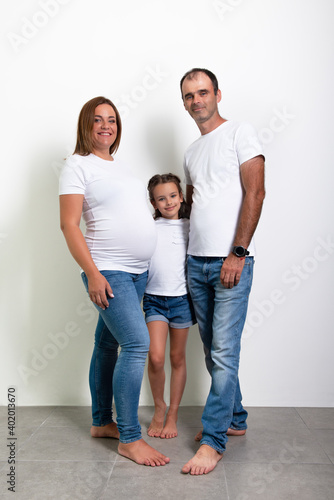 Pregnant mother, father and daughter posing at home. Pregnancy.