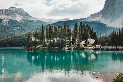 Red canoes paddle around the peninsula of the famous Emerald Lake on a bright, cloudy summer day in Yoho National Park, BC, Canada.