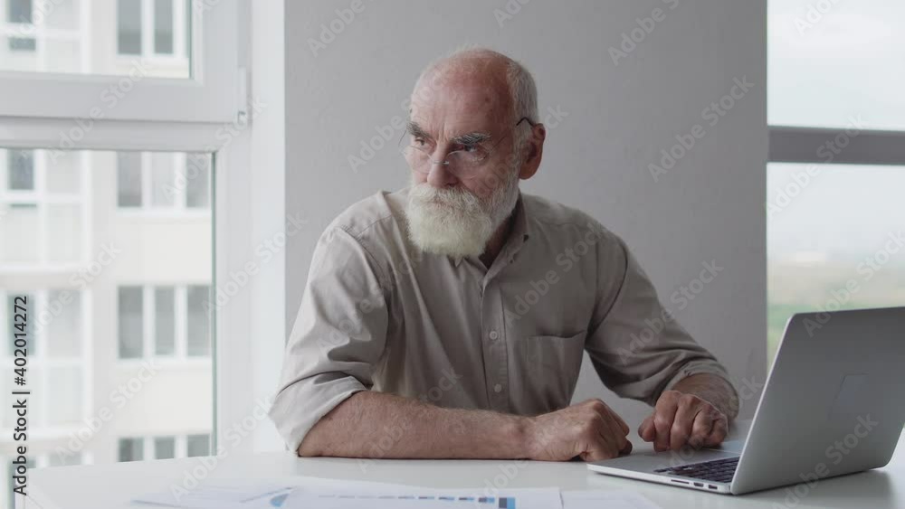 Nervous senior man worker typing on laptop, making report looking at diagram Nervous senior man worker typing on laptop, making report looking at diagram