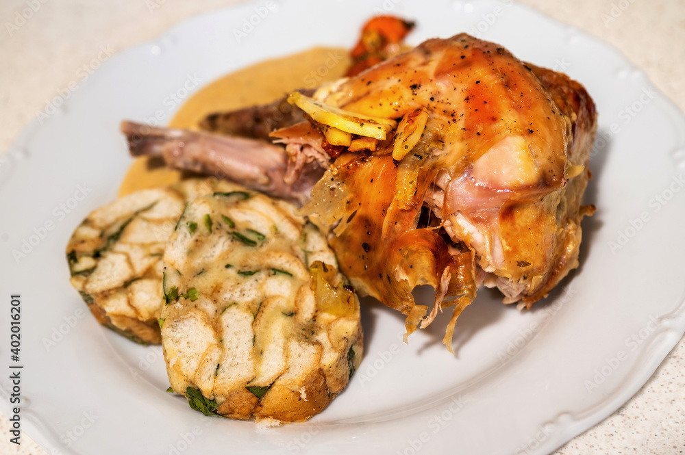 Baked rabbit leg with vegetable cream sauce and Carlsbad dumpling on white plate. Baked rabbit leg with vegetable cream sauce and Carlsbad dumpling on white plate.