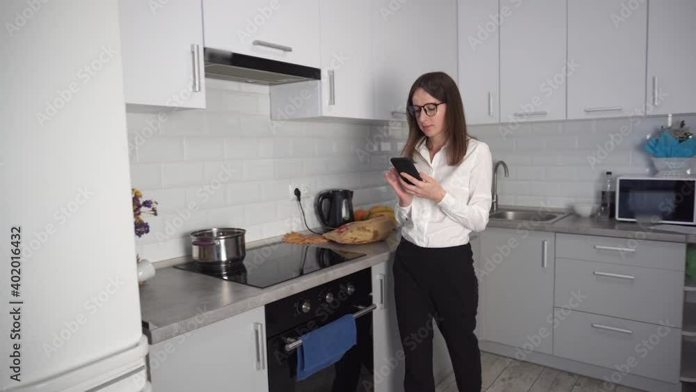Portrait of attractive woman texting message on smartphone at kitchen. Thoughtful lady using cellphone at home. Portrait of attractive woman texting message on smartphone at kitchen. Thoughtful lady using cellphone at home.