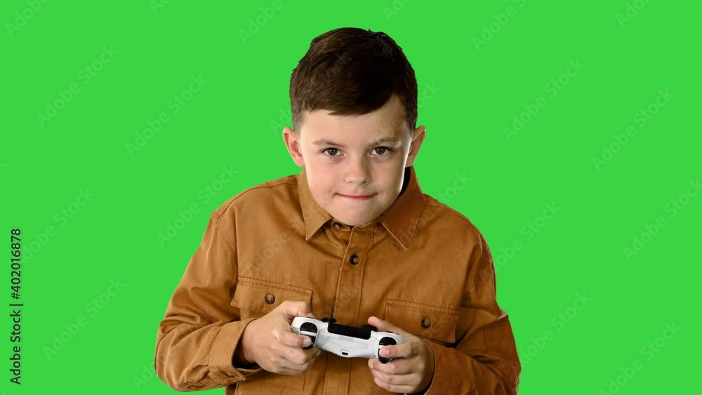 Emotional little boy playing video games with joystick in his hands on a Green Screen, Chroma Key.