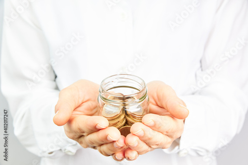 Hand with coins in a glass jar. Money growth and savings concept